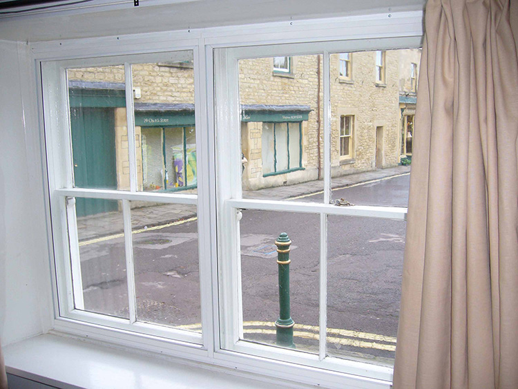 White horizontal sliding secondary glazing fitted behind an existing bedroom window